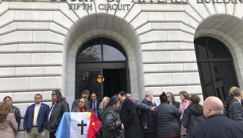 Rosa Soto Alvarez, of Tucson,, holds a flag of the Pascua Yaqui Tribe as she and other Native Americans stand outside the federal appeals court in New Orleans, Wednesday, Jan. 22, 2020. (AP)