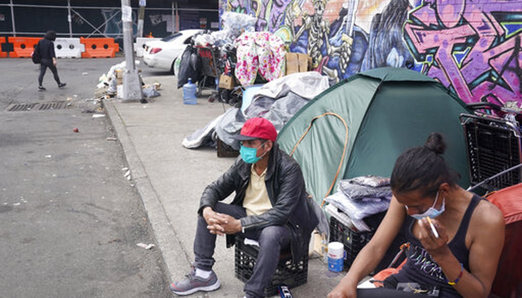 Sotero Cirilo, center, sits on the sidewalk at a homeless encampment where he sleeps in Queens, New York, on April 14, 2021. (AP)
