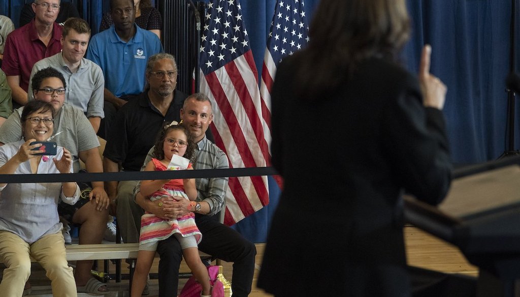 Stella Quatrini, center, is held as she watches Vice President Kamala Harris speak about the child tax credit during an event at Brookline Memorial Recreation Center in Pittsburgh, June 21, 2021. (AP)