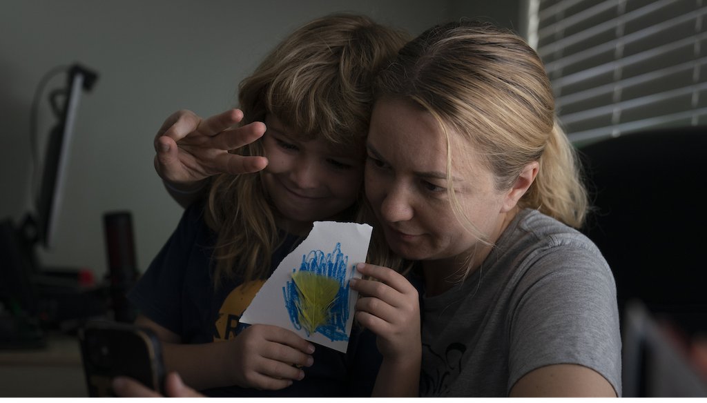 With son, Volodymyr, holding a Ukrainian flag he made, Hanna Tverdokhlib, a 37-year-old Ukrainian immigrant, flashes a three-finger salute to her sister on a video chat in her apartment in Long Beach, Calif March 1, 2022. (AP)