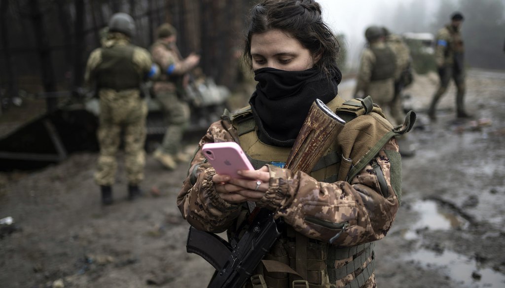 Ukrainian army soldier checks her phone after a military sweep to search for Russian troops, Friday, April 1, 2022. (AP)