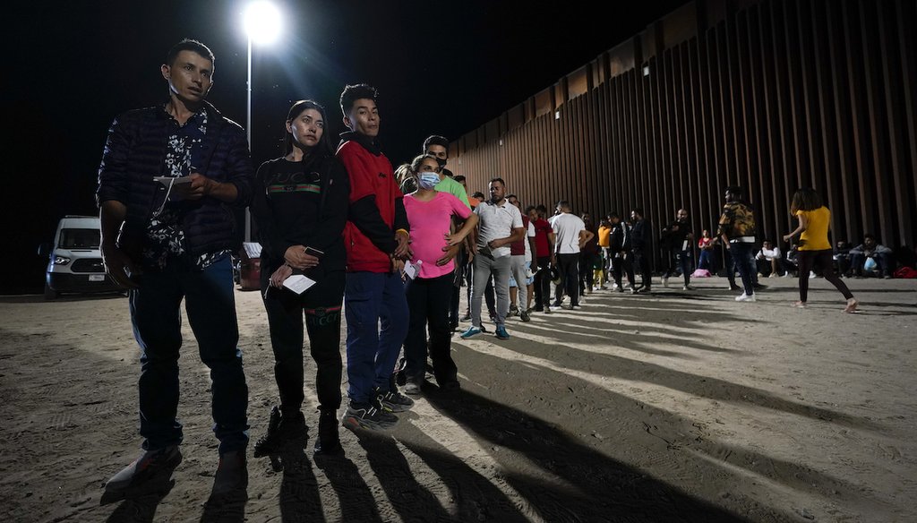 Migrants wait along a border wall on Aug. 23, 2022, after crossing from Mexico near Yuma, Ariz. (AP)