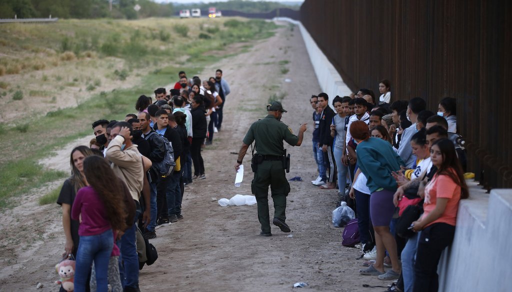 A group of migrants stand next to the border wall as a Border Patrol agent takes a head count in Eagle Pass, Texas, May 21, 2022. (AP)