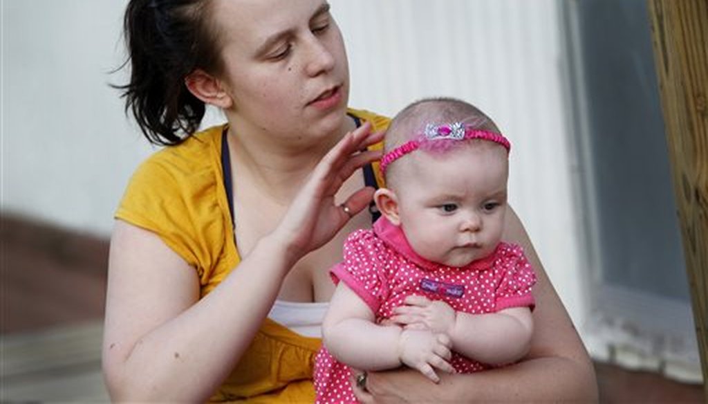 A 22-year-old former foster child, Megan Moore, adjusts a hair band on her 5-month-old daughter, Constance, at their home in Kenova, W.Va., in 2013. (AP)