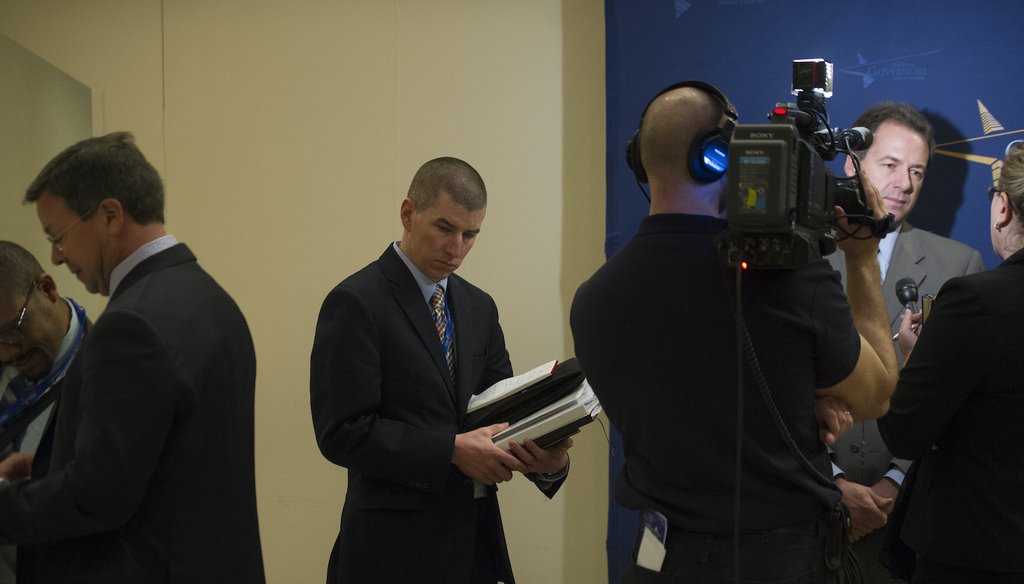 Kevin O'Brien, former deputy chief of staff, center, to Montana Gov. Steve Bullock, at right, holds briefing books as Bullock is interviewed by a television crew in 2014. (AP)