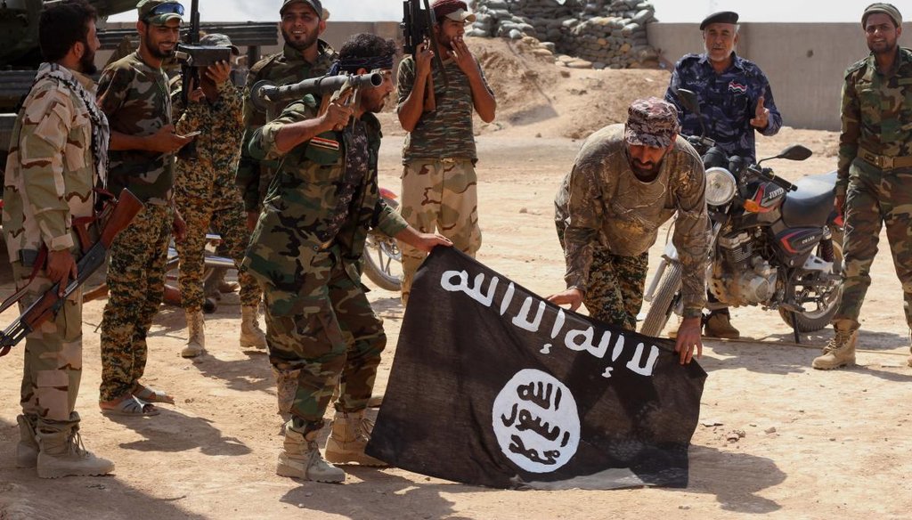 Iraqi security forces hold a flag of the Islamic State group they captured during an operation outside Amirli, some 105 miles north of Baghdad, Iraq, Sept. 1, 2014. (AP)