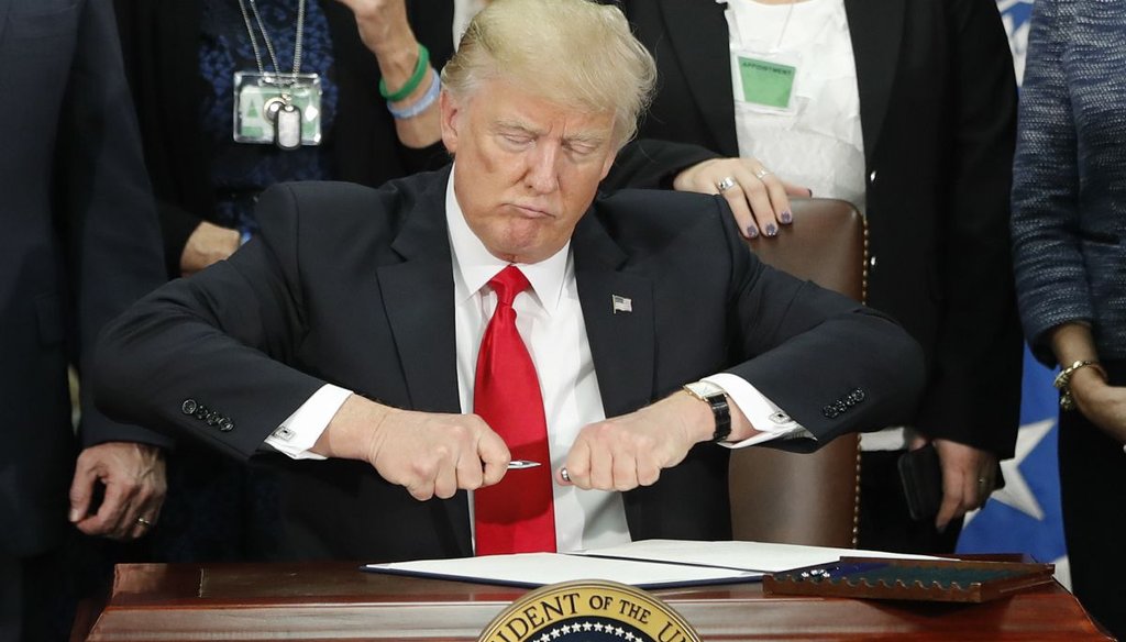 President Donald Trump takes the cap off a pen before signing executive order for immigration actions to build border wall during a visit to the Homeland Security Department in Washington, Wednesday, Jan. 25, 2017. (AP Photo/Pablo Martinez Monsivais) 