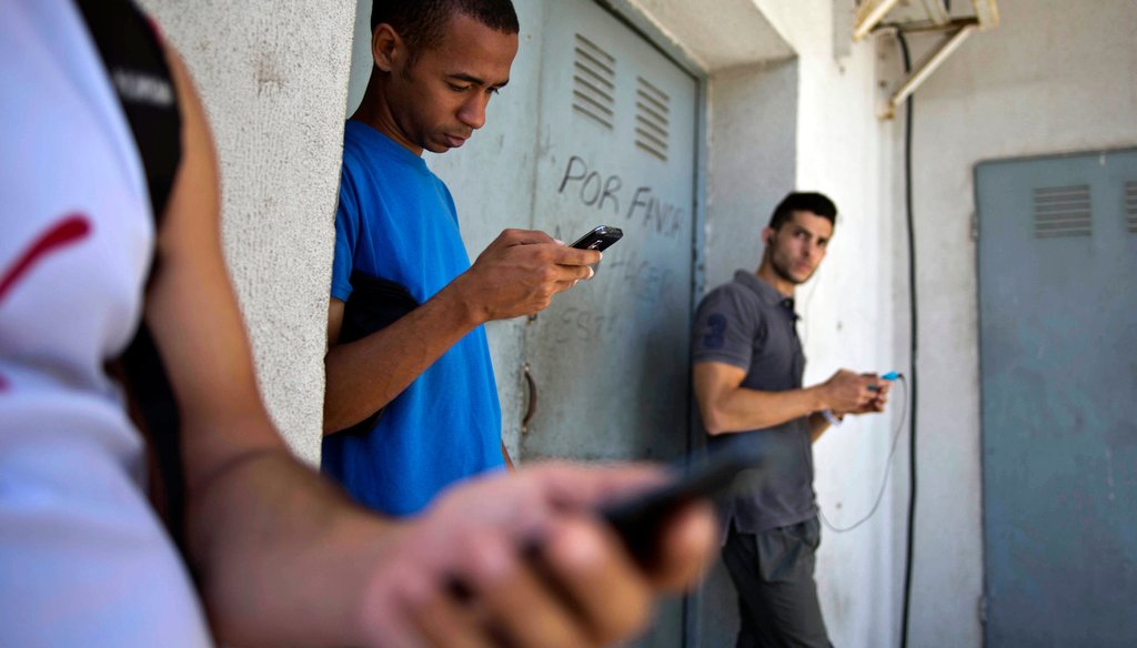 Students stand outside a building to find an Internet signal for their phones in Havana, Cuba, on April 1. (AP Photo) 