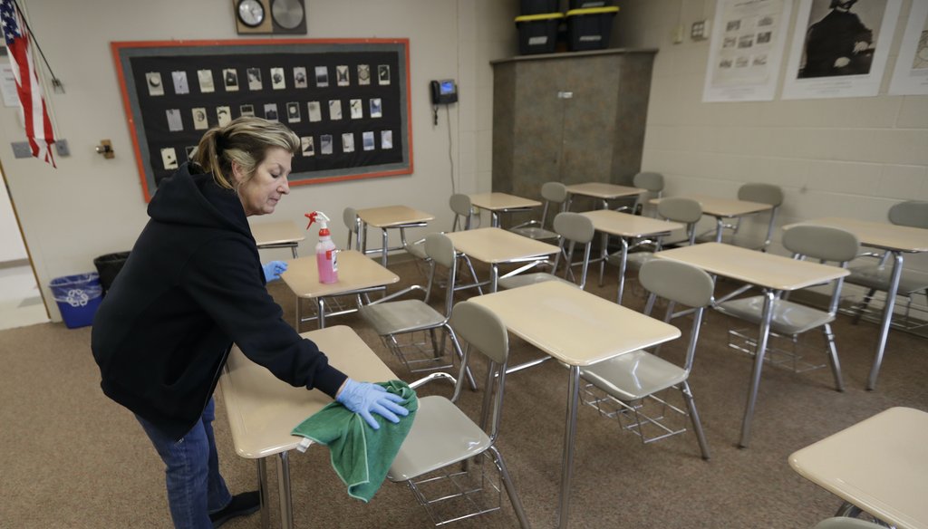 Custodian Patti Alesci cleans desks at Orange High School, Monday, March 16, 2020, in Pepper Pike, Ohio. (AP)