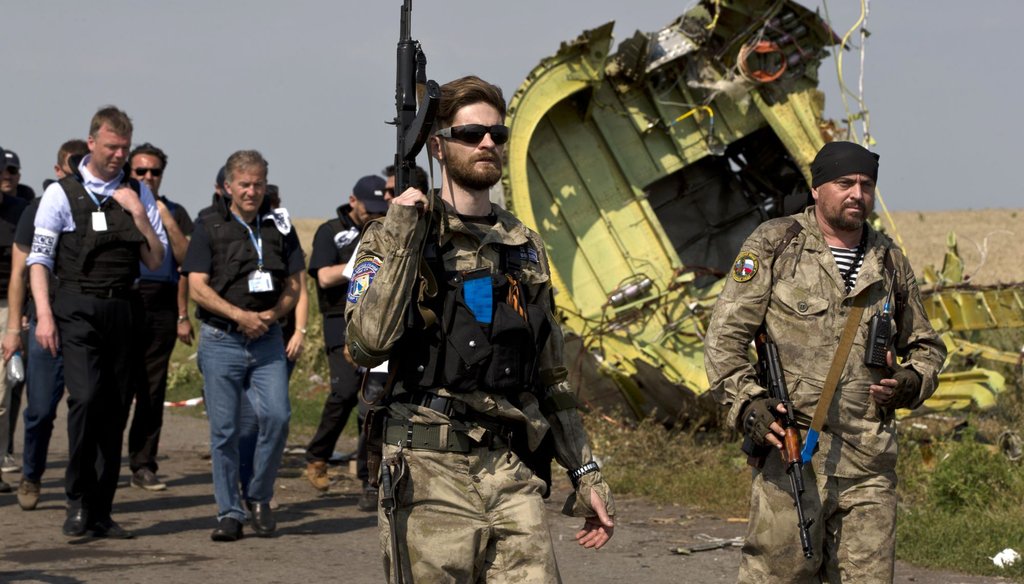Pro-Russian rebels, right, walk by plane wreckage as they arrive for a media briefing at the crash site of Malaysia Airlines Flight 17 on July 22, 2014. (AP Photo)