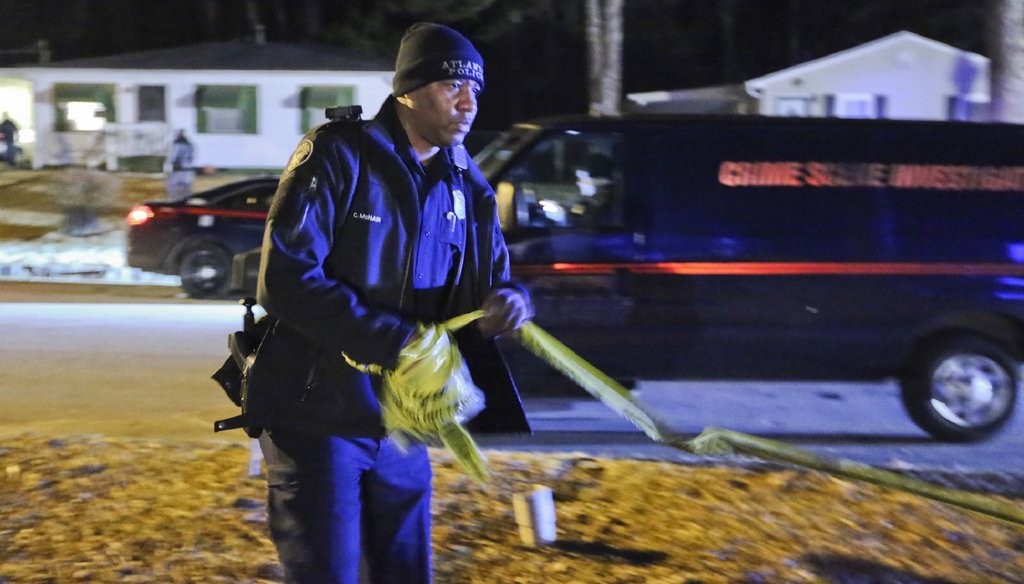 An Atlanta police officer gathers crime scene tape after the shooting investigation of a man found dead inside a vehicle in a city driveway in February. Photo by John Spink / AJC
