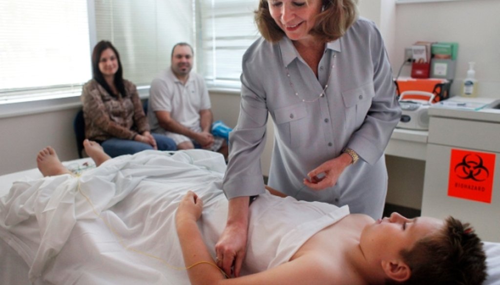 Beata and Alex Karaszi, left, watch as their son Alex Karaszi gets an acupuncture treatment from Dr. Laura Weathers in Tampa. (Kathleen Flynn/Tampa Bay Times)