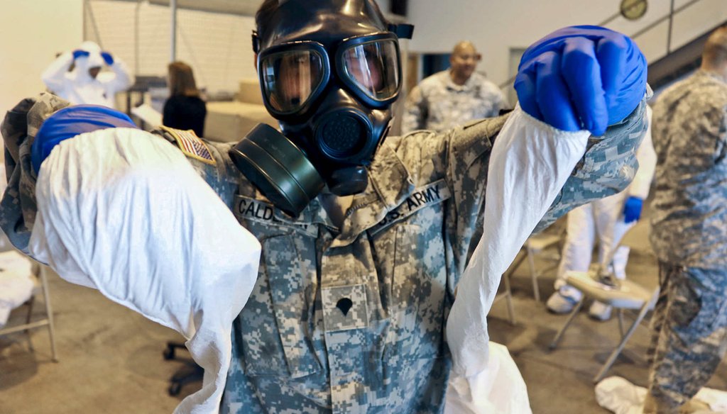 Army Spc. Kristal Calderon practices donning and removing protective equipment and a mask after a class at the logistical warehouse on Fort Gordon, Ga., Oct. 14, 2014.(U.S. Army)