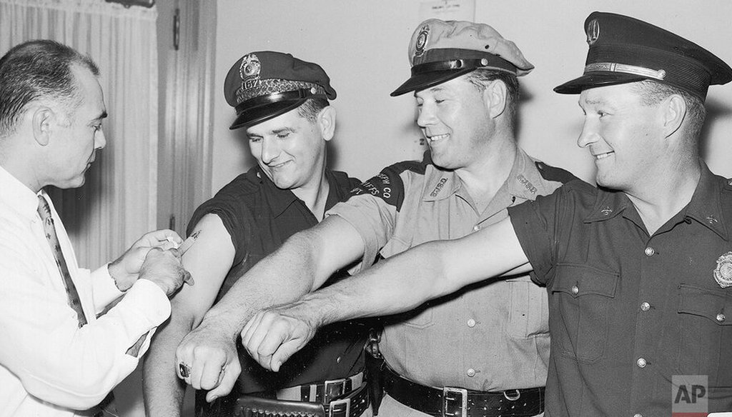 The first four of more than 500 police, firemen and deputy sheriffs in St. Joseph County to receive Asian flu vaccine bare their arms for Dr. William J. Stogdill in South Bend, Ind., on Aug. 30, 1957. (AP)