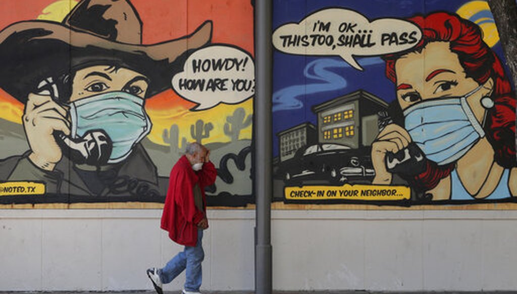 A man wearing face protection walks past a mural painted on a border up business closed due to the COVID-19 pandemic, Monday, April 27, 2020, in Austin, Texas. (AP)