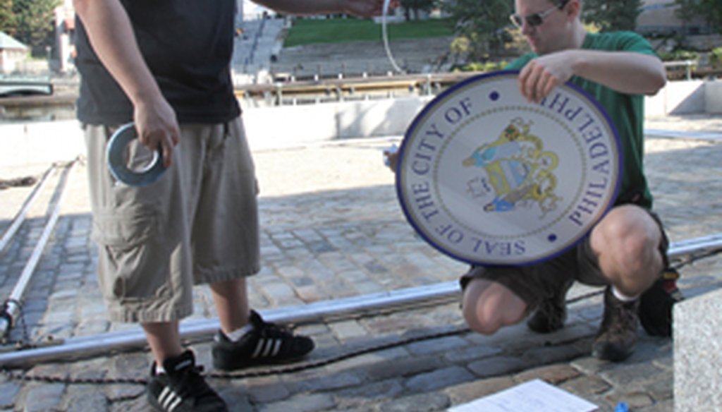 Two members of the New England Stage Mechanics Union prepare a sign of the seal of the City of Philadelphia to be placed over a City of Providence seal at Waterplace last year during a day of filming for the ABC-TV show "Body of Proof." 