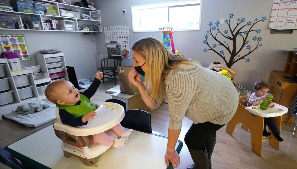 Amy McCoy signs to a baby about food as a toddler finishes lunch behind at her Forever Young Daycare facility on Oct. 25, 2021, in Mountlake Terrace, Wash. (AP)