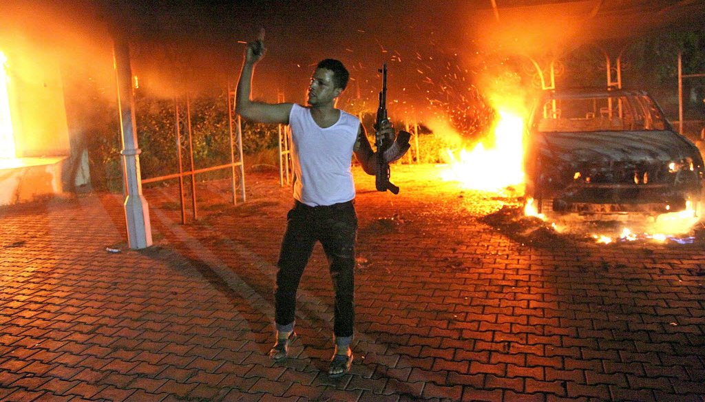 An armed man waves his rifle as buildings and cars are engulfed in flames after being set on fire inside the U.S. compound in Benghazi, Libya, late on Sept. 11, 2012. 
