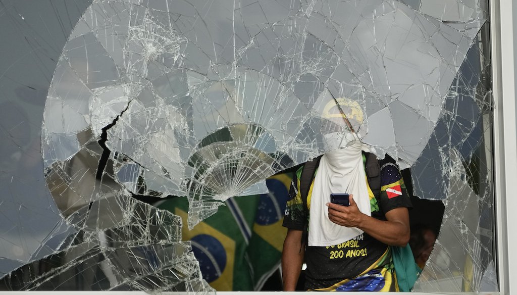 A supporter of Brazil's former President Jair Bolsonaro looks out from a broken window in the Planalto Palace. On Jan. 8, pro-Bolsonaro protesters broke into and stormed the building after the inauguration of President Luiz Inácio Lula da Silva. (AP)