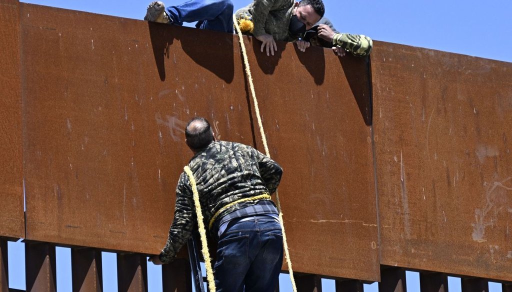 People use a ladder to scale the border fence at the U.S.-Mexico border in Tecate, Mexico on April 21, 2022. (AP)