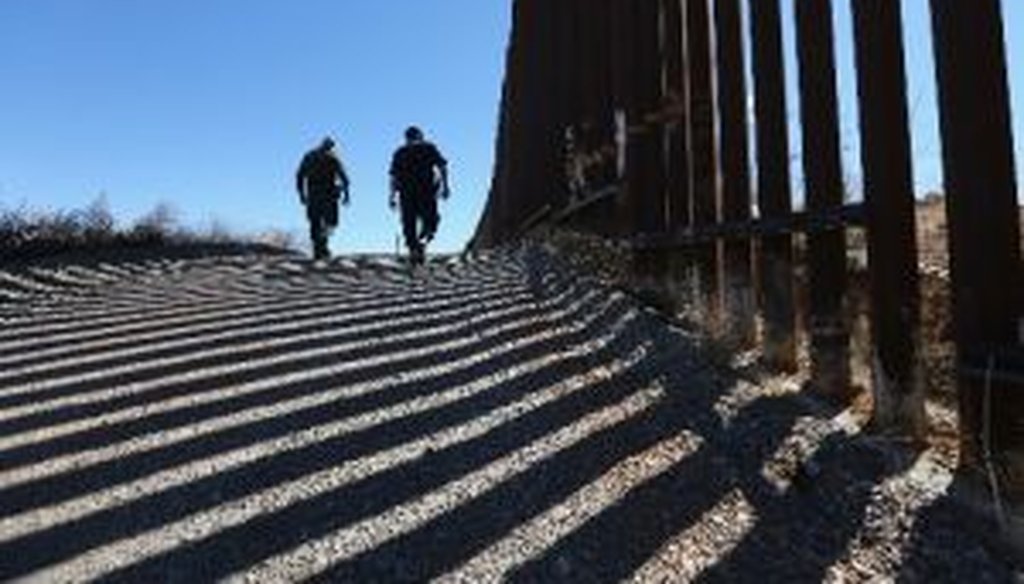 U.S. Customs and Border Protection personnel walk along a section of recently-constructed fence on the U.S.-Mexico border near Nogales, Ariz. 