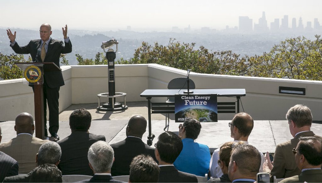 California Gov. Jerry Brown, at podium, speaks before signing a bill to combat climate change by increasing the state's renewable electricity use to 50 percent. Damian Dovarganes / AP