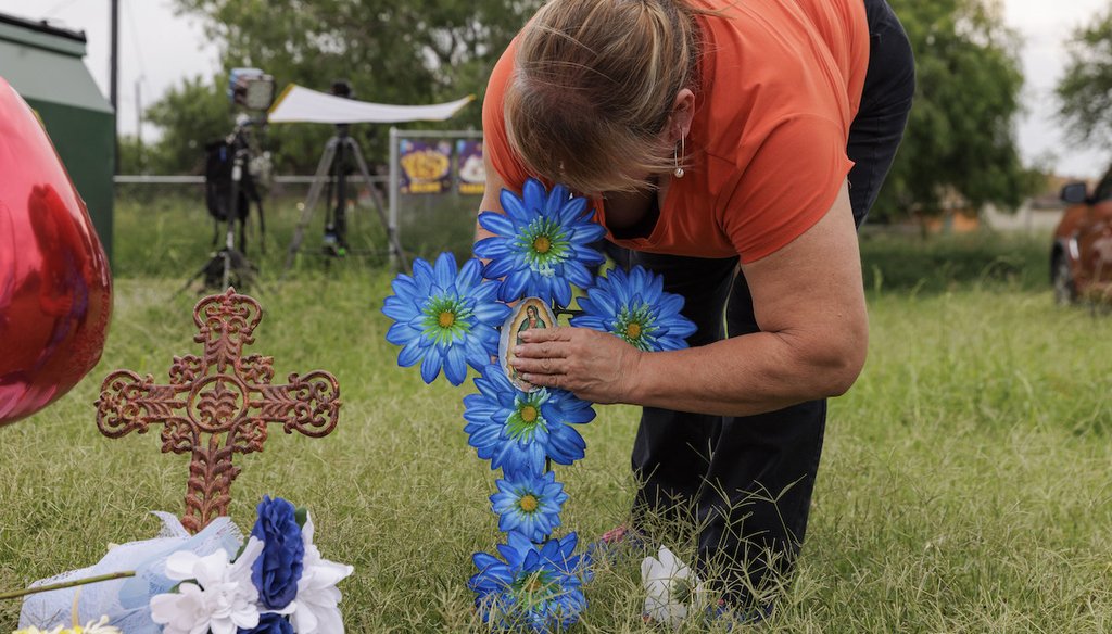 Rosario De La Cruz places a flower arrangement in the shape of a cross at a memorial site where eight migrants were killed and several others injured the day before while waiting at a bus stop in Brownsville, Texas, Monday, May 8, 2023. (AP)