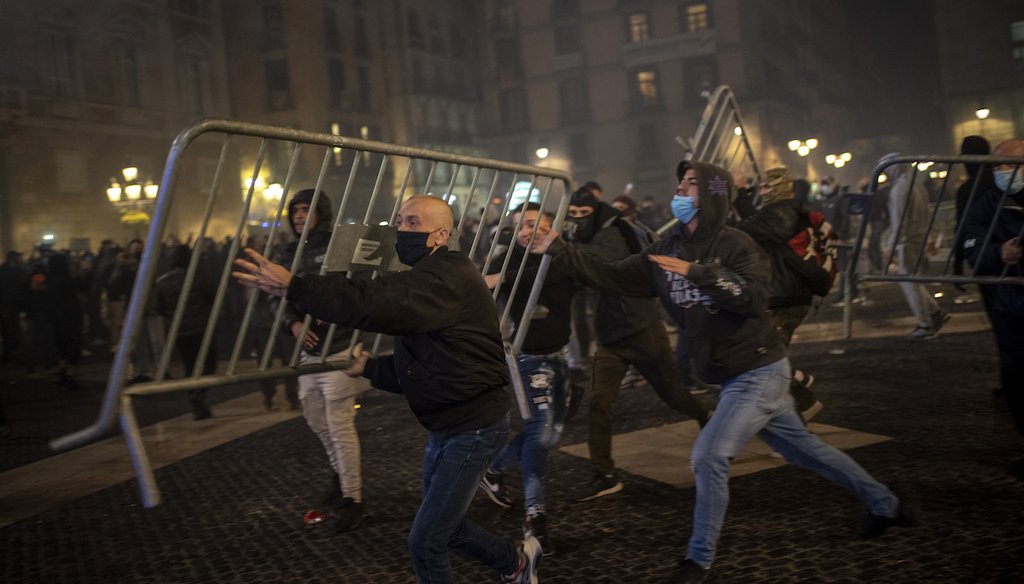 Demonstrators throw metallic fences against police during clashes in downtown Barcelona, Spain, Friday, Oct. 30, 2020. An Instagram post claimed to show a video of migrants looting a store. But the video was from this protest. (AP)