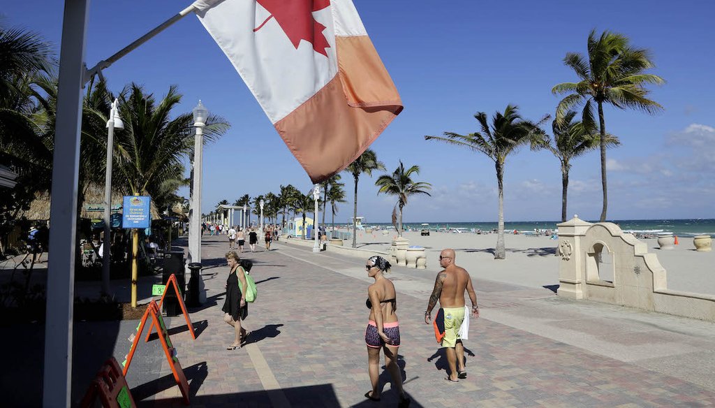 In this Nov. 23, 2015 photo, a Canadian flag flies as people walk along the boardwalk in Hollywood, Fla. (AP)
