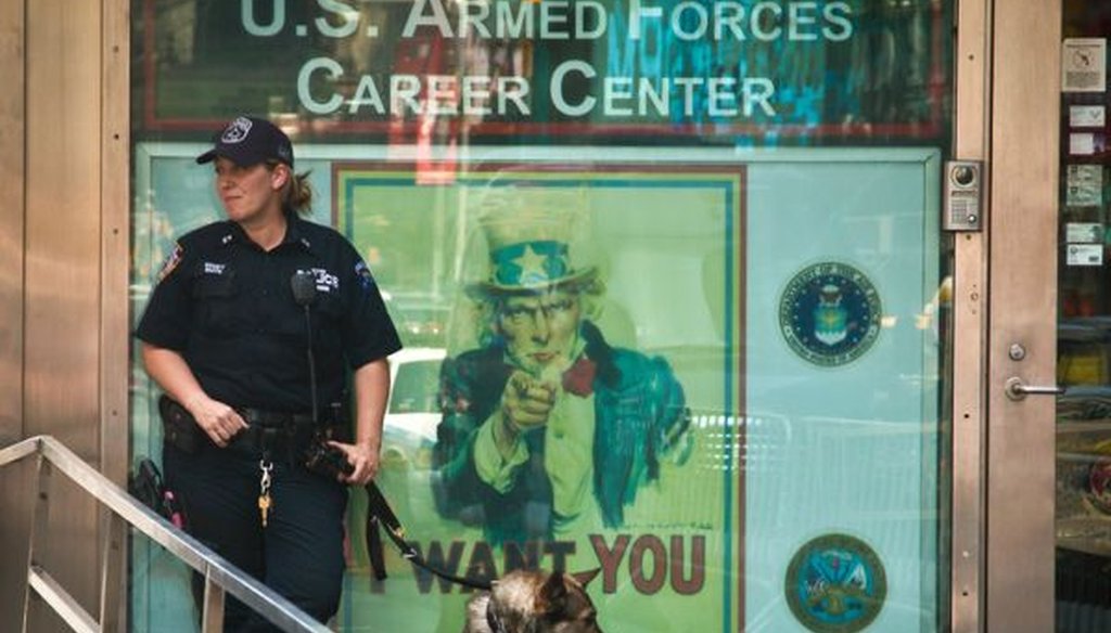 An NYPD anti-terrorism officer stands guard with a K-9 unit at a military recruiting station in Times Square, on July 17, 2015. Security at military recruiting centers will be reviewed in the aftermath of a shooting in Tennessee. (AP/Bebeto Matthews)