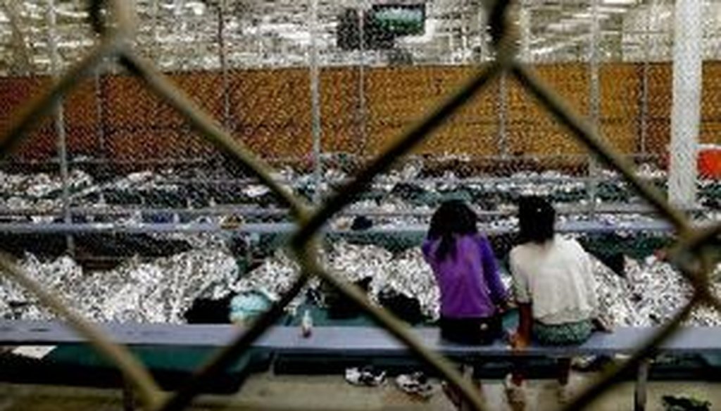Two girls watch a World Cup soccer match from their holding area in Nogales, Ariz., where hundreds of mostly Central American immigrant children are being processed and held.