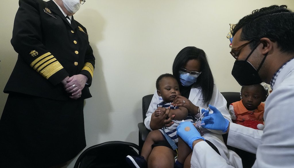 On June 28, 2022, in Miami, Florida, Pediatrician Emy Jean-Marie, center, holds her nine-month-old son Adedeji Adebayo, on her lap as Dr. Nizar Dowla, right, administers a vaccine. (AP)