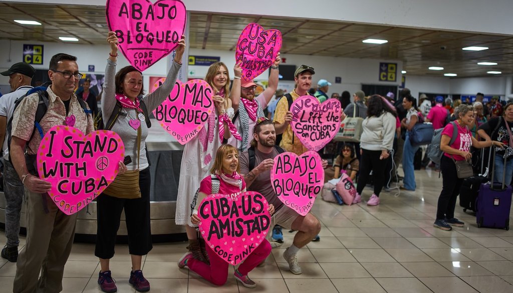Activists from CODEPINK, including co-founder Medea Benjamin, kneeling center, and others hold signs as part of the "Nuestra America" convoy at the airport in Havana, Cuba, on March 20, 2026. (AP)