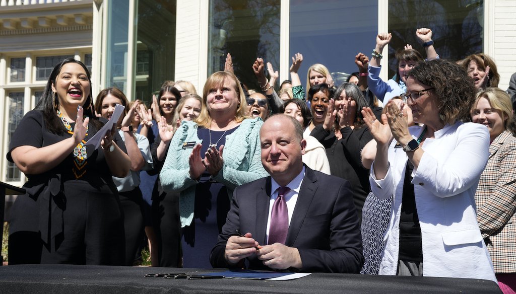 Colorado Gov. Jared Polis, front, signs into law the Reproductive Health Equity Act during a ceremony outside the governor's mansion, Monday, April 4, 2022, in Denver. (AP)