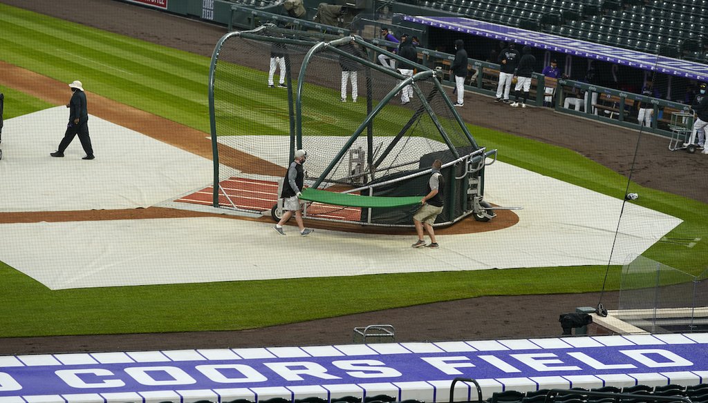 Grounds crew workers prepare to pull the tarpaulin as a light rain descends on Coors Field in Denver on April 6, 2021. Major League Baseball decided to move its 2021 All-Star Game to Denver from Atlanta as a result of changes in Georgia's voting law. (AP)