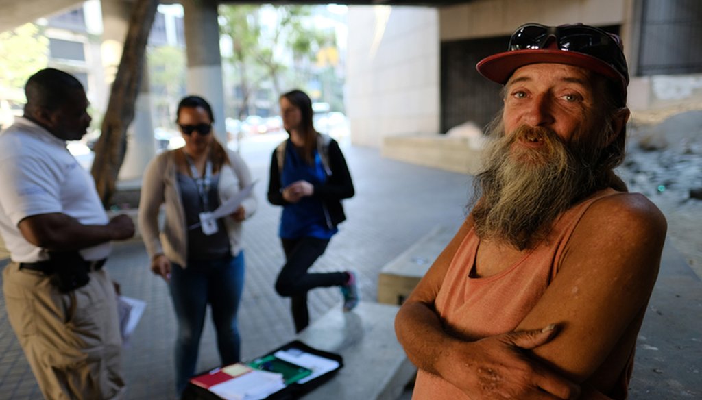 In this Friday, June 17, 2016 photo, homeless man David Brophy, right, talks to People Assisting The Homeless (PATH) outreach team members who are helping him acquire an ID card on a street near where he lives in Los Angeles. (AP Photo/Richard Vogel)