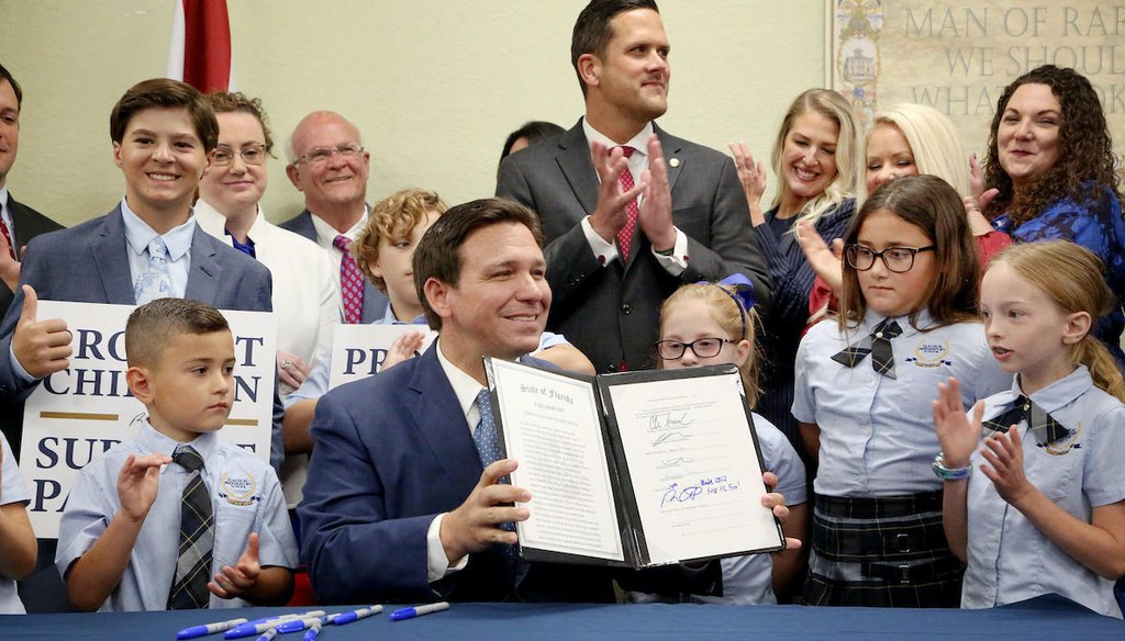 Florida Gov. Ron DeSantis displays the signed Parental Rights in Education law flanked by elementary school students during a news conference March 28, 2022, at Classical Preparatory school in Shady Hills, Fla. (Douglas R. Clifford/Tampa Bay Times)