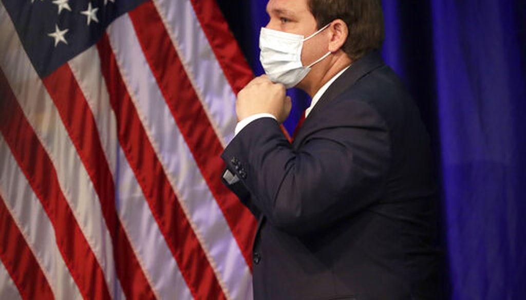 Florida Gov. Ron DeSantis puts on his mask to protect against the new coronavirus as he leaves a news conference on COVID-19, Friday, June 19, 2020, at Florida International University in Miami. (AP)