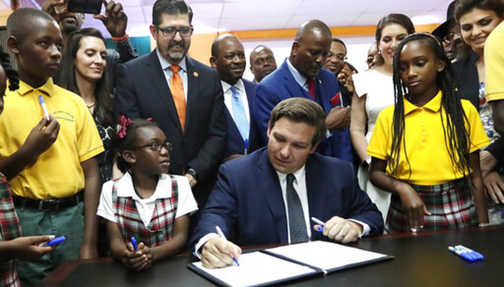 Florida Gov. Ron DeSantis, center, signs a bill at the William J. Kirlew Junior Academy, May 9, 2019, in Miami Gardens, Fla. The bill creates a new voucher program for thousands of students to attend private schools. (AP)