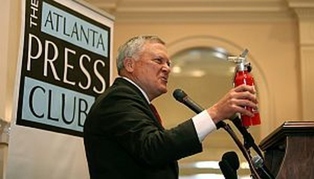 Georgia Gov. Nathan Deal brings out his fire extinguisher during his speech at the Atlanta Press Club on April 30, 2013. The governor was prepared to put out the flames of any “Pants on Fire” violator. (AJC photo/Jason Getz)