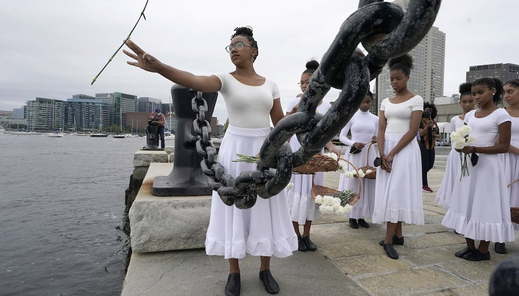 A dancer throws carnations into Boston Harbor, Sunday, Aug. 29, 2021, in a ceremony honoring Africans who survived or perished during the transatlantic voyage into American slavery. Flowers were thrown in remembrance of their lives and deaths. (AP)
