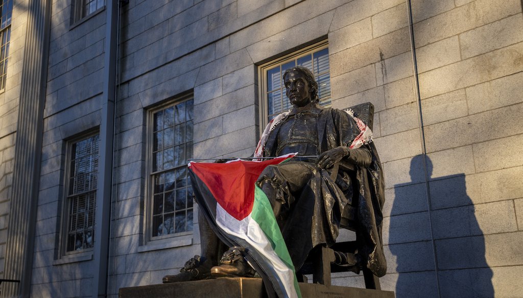La estatua de John Harvard, primer gran benefactor del Harvard College, envuelta por la bandera palestina, durante las protestas estudiantiles contra la guerra en Gaza, en la Universidad de Harvard en Cambridge, Massachusetts, el 25 de abril de 2024. (AP)