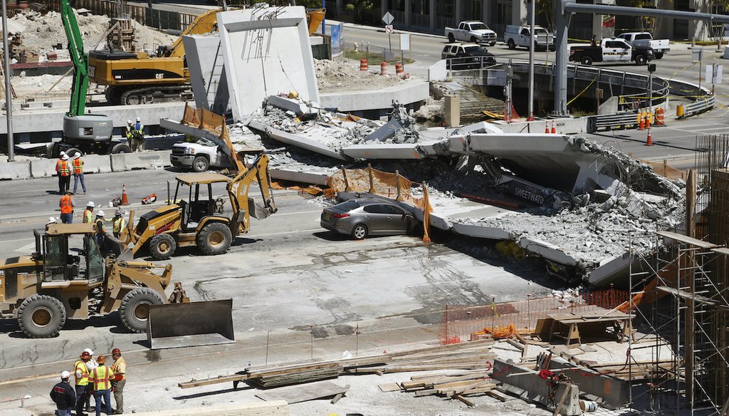 Crushed cars are shown under a section of a collapsed pedestrian bridge, Friday, March 16, 2018 near Florida International University in the Miami area. (AP)