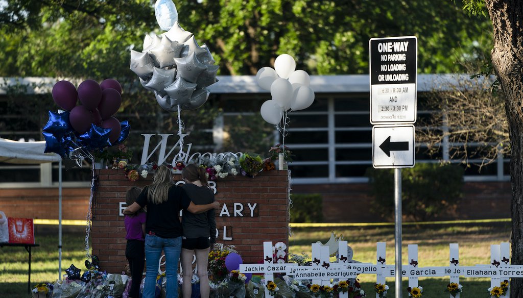 A family pays their respects next to crosses bearing the names of Tuesday's shooting victims at Robb Elementary School in Uvalde, Texas, on May 26, 2022. (AP)