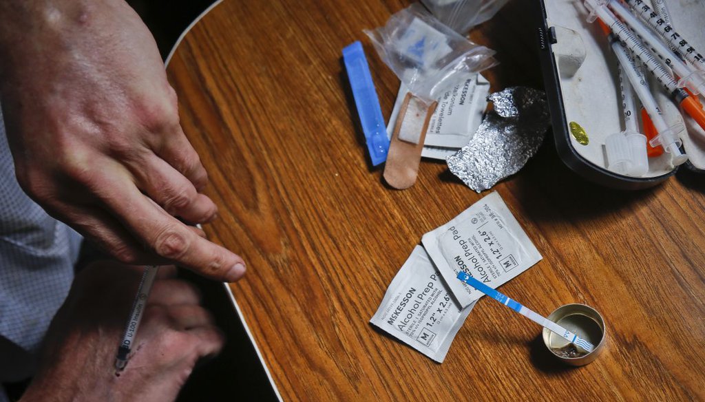 A person injects heroin as a fentanyl test strip registers a positive result for contamination. (AP)