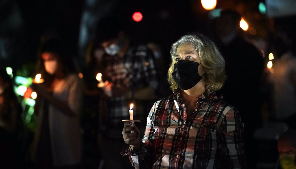 A woman wears a protective face mask while holding a candle during an outdoor Christmas Eve Service of Lights at the Granada Presbyterian Church, Thursday, Dec. 24, 2020, in Coral Gables, Fla. The service was held outdoors for COVID-19 safety. (AP)