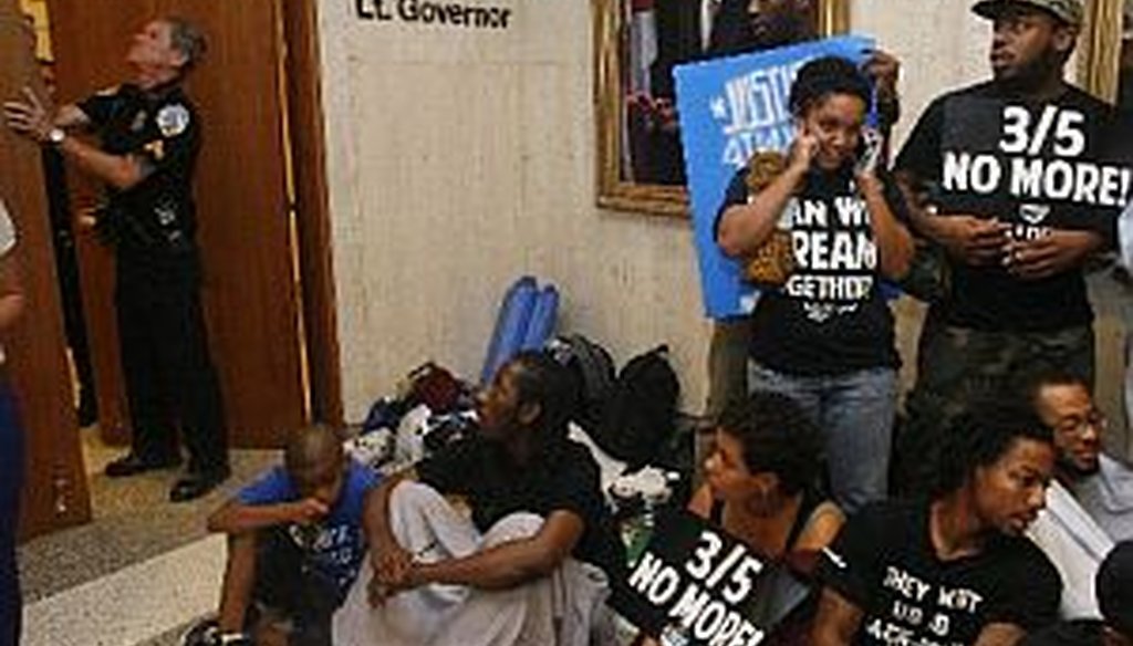 A police officer closes Florida Gov. Rick Scott's office at 5 p.m. on July 16, 2013, as protestors sit in the hallway at the Capitol in Tallahassee, Fla. 