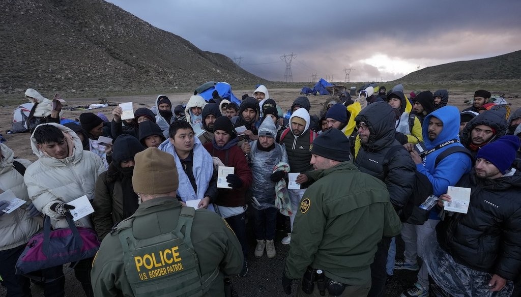 Agentes de la Patrulla Fronteriza de EE.UU. hablan con migrantes que buscan asilo, principalmente de Colombia, China y Ecuador, en un campamento improvisado y montañoso tras cruzar la frontera entre México y EE.UU., el 2 de febrero de 2024 (AP).