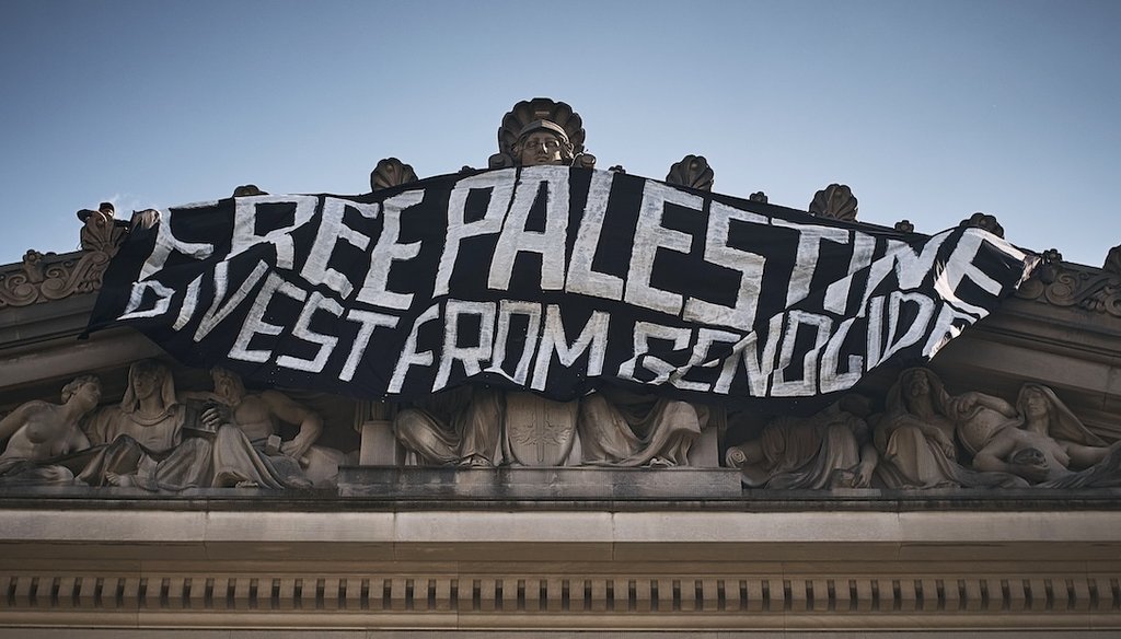 A demonstrator, upper left, hangs a flag on top of the Brooklyn Museum during a protest demanding a permanent cease-fire in Gaza, May 31, 2024, in New York. (AP)