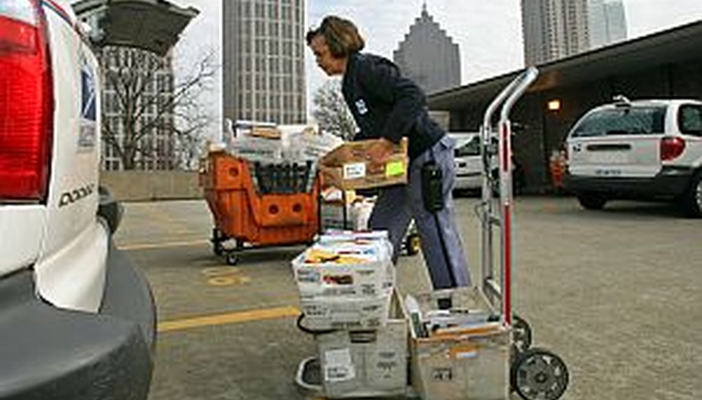 Mail carrier Annie Johnson gathers mail for her routes at the post office in midtown Atlanta.  The American Postal Workers Union says the Postal Service is funded through stamps and postage, and doesn’t run on tax dollars. (AJC photo/Jason Getz) 